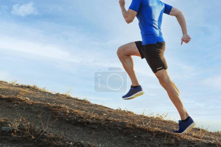 male runner run steep mountain climb on trail in blue sky background, overcoming difficulties in sports