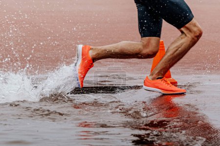 Foto de Piernas atleta masculino corredor corriendo carrera de obstáculos, competición de atletismo campeonato, salpicaduras de agua - Imagen libre de derechos