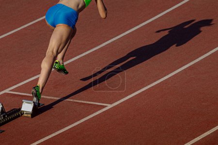 Téléchargez les photos : Départ athlète féminine des blocs de départ course sprint distance, ombre femme coureur sur la piste du stade - en image libre de droit