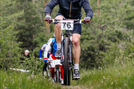 Photo for Athlete leader cyclist ahead group of mountain bikers riding cross-country cycling competition - Royalty Free Image
