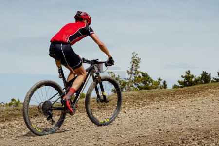 Foto de Ciclismo de fondo, ciclista atleta montar bicicleta de montaña cuesta arriba en la carretera de grava - Imagen libre de derechos