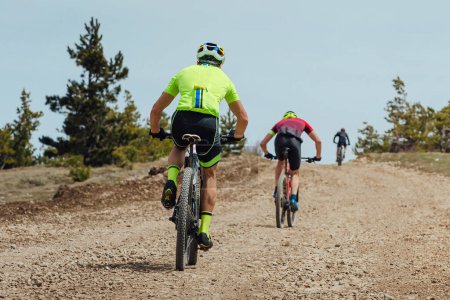Téléchargez les photos : Vue arrière groupe athlète cycliste équitation VTT montée, vélo sur route de gravier, compétition cycliste - en image libre de droit