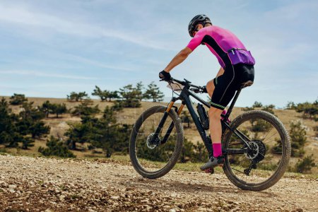 Photo for Athlete mountainbiker biking uphill in cross-country cycling, outdoors summer race - Royalty Free Image