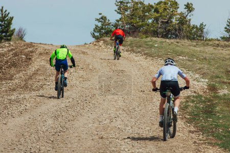 Téléchargez les photos : Vue arrière trois vététistes en montée à vélo, vélo sur route de gravier, compétition cycliste - en image libre de droit