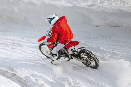 Photo for Motocross rider riding sharp turn winter motorcycle racing, snow splashes from under rear wheel - Royalty Free Image