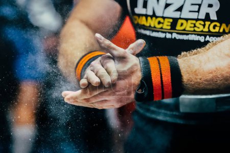 Photo for Male powerlifter apply gym chalk on hands for bench press powerlifting. Inzer singlet and wrist wraps - Royalty Free Image