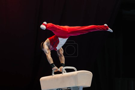Photo for Male gymnast performing on pommel horse competition artistic gymnastics, black background - Royalty Free Image