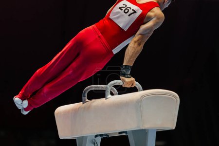 Photo for Close-up gymnast performing on pommel horse competition artistic gymnastics, black background - Royalty Free Image