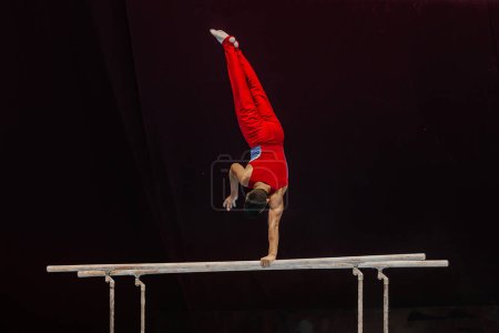 Photo for Male gymnast performing on parallel bars competition artistic gymnastics, black background - Royalty Free Image