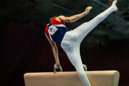 Téléchargez les photos : Vue arrière gymnaste performant sur pommeau cheval compétition gymnastique artistique, fond noir - en image libre de droit