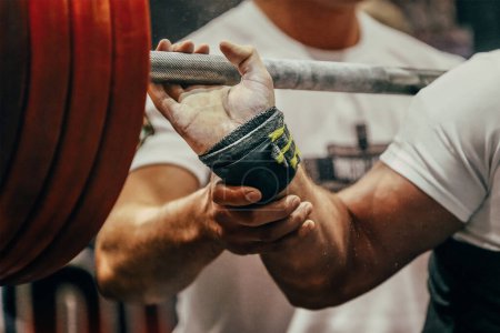 Photo for Arm powerlifter in wrist wraps to hold heavy barbell before squatting powerlifting competition - Royalty Free Image