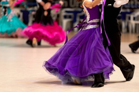 Foto de Jóvenes parejas bailarines bailando vals en la competencia de dancesport, vestidos de colores para las niñas y negro traje de cola para niños - Imagen libre de derechos