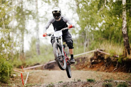 Téléchargez les photos : Descente coureur de vélo de montagne sauter par-dessus le tremplin dans la course de sentier forestier - en image libre de droit
