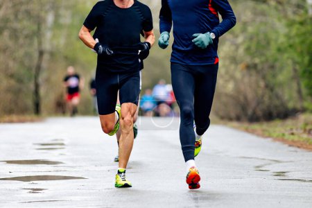 Téléchargez les photos : Vue de face deux coureurs masculins courir printemps courir sur la route avec des flaques - en image libre de droit
