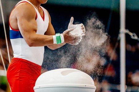 Téléchargez les photos : Gros plan mains gymnaste masculin en poignées de gymnastique appliquer la craie de gymnastique de la magnésie stands - en image libre de droit
