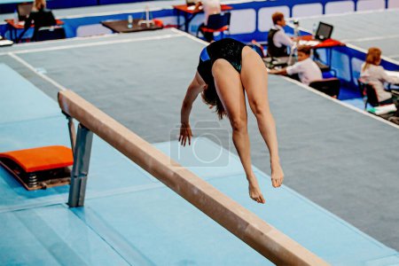 Téléchargez les photos : Gymnaste féminin exercice élément acrobatique sur faisceau d'équilibre en gymnastique artistique, jeux de sport d'été - en image libre de droit