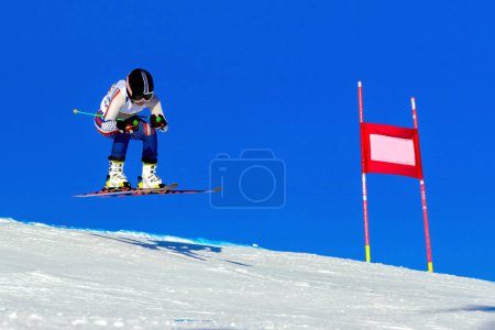 Foto de Atleta esquiadora femenina en pista de esquí alpino, pista nevada sobre fondo azul cielo, juegos de deportes de invierno - Imagen libre de derechos