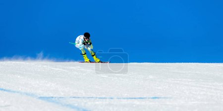 Téléchargez les photos : Skieur masculin sur piste de ski alpin, piste enneigée sur fond de ciel bleu, jeux de sports d'hiver - en image libre de droit