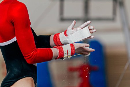 Photo for Close-up hands female gymnast in gymnastics grips in gym chalk, uneven bars performing - Royalty Free Image