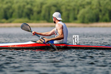 Photo for Side view male kayaker athlete on kayak single in kayaking championship race, boat number 13 - Royalty Free Image