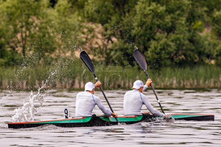 Téléchargez les photos : Vue de côté kayakistes mâles en kayak double en course de compétition de kayak, éclaboussures d'eau des pagaies - en image libre de droit