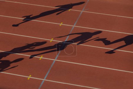 Foto de Negro silueta grupo femenino corredores en rojo pista estadio corriendo carrera de sprint - Imagen libre de derechos