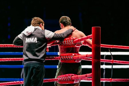 Photo for Rear view coach and fighter stand in red corner ring in MMA fighting, hoodie with inscription MMA - Royalty Free Image