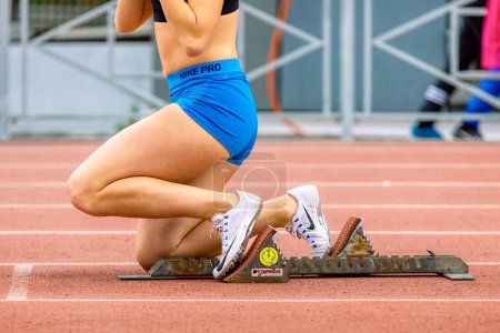 Photo for Close-up legs female runner in starting blocks Polanik, Nike spikes shoes and Nike Pro blue shorts, sprint race in athletics - Royalty Free Image