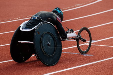 Photo for Rear view para athlete in wheelchair racing riding on red track stadium, summer para athletics championships - Royalty Free Image