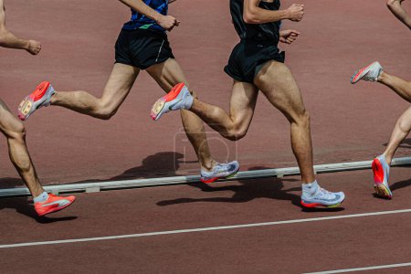 Photo for Group male runner in Nike and Puma spikes shoes middle-distance running at track stadium in summer athletics championships - Royalty Free Image