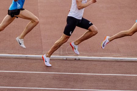 Photo for Legs male runner in Nike spikes shoes middle-distance running at stadium in summer athletics championships - Royalty Free Image