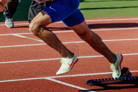 Téléchargez les photos : Jambes homme sprinteur coureur dans Nike pointes chaussures courir dans les blocs de départ course, championnats d'athlétisme d'été - en image libre de droit