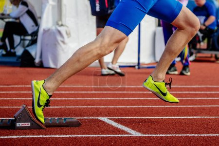 Photo for Legs male athlete start running in Polanik starting blocks sprint race, Nike spikes shoes - Royalty Free Image