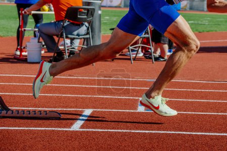 Foto de Piernas atleta masculino empezar a correr en los bloques de partida carrera de sprint, zapatos Nike Spikes - Imagen libre de derechos