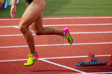 Photo for Legs female runner starting run race red track stadium, summer athletics championships, Nike brand running spikes shoes - Royalty Free Image
