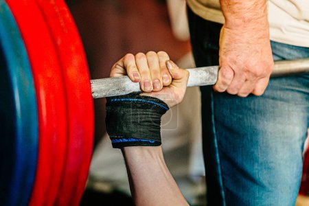 Photo for Close-up hand male powerlifter in wrist wraps holding barbell, bench press powerlifting competition - Royalty Free Image