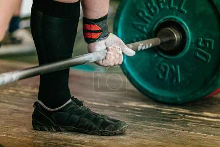 Photo for Athlete powerlifter performing deadlift heavy barbell, hand in wrist wraps with applied gym chalk - Royalty Free Image