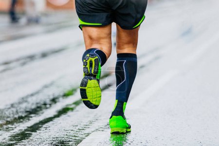 Téléchargez les photos : Gros plan jambes coureur athlète marathon de course en chaussettes de compression noires, course masculine sur asphalte mouillé - en image libre de droit