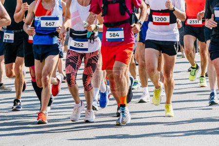 Foto de Grandes grupos corredores atletas hombres y mujeres corren maratón de la ciudad carrera, números en camisas, juegos de deportes de verano - Imagen libre de derechos
