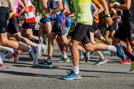 Téléchargez les photos : Coureurs de grands groupes courir course de marathon de la ville, jambes athlètes masculins en chaussures de course Asics, Adidas, Hoka, Nike - en image libre de droit