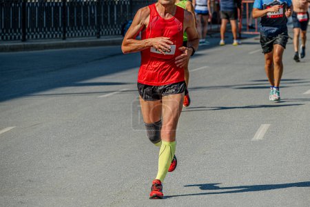 Téléchargez les photos : Athlète coureur masculin en chaussettes de compression et genouillères course de marathon de course, jeux d'été sportifs - en image libre de droit