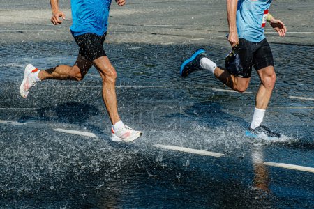 Téléchargez les photos : Deux coureurs masculins courent marathon course dans la station d'eau, flaque d'eau et éclaboussures d'eau - en image libre de droit