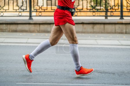 Foto de Vista lateral corredor masculino carrera maratón en calcetines de compresión blancos y zapatos de running de color rojo brillante - Imagen libre de derechos