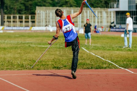 Téléchargez les photos : Athlète masculin sans jambe avec béquille lancer de javelot aux championnats d'athlétisme, jeux de sport d'été - en image libre de droit