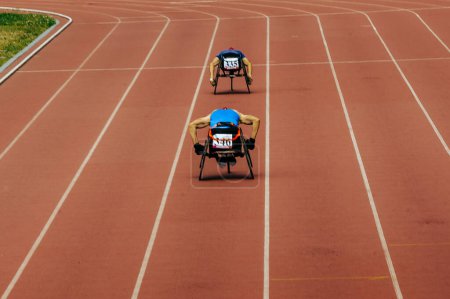 Téléchargez les photos : Deux athlètes dans le stade de course en fauteuil roulant piste de course dans le championnat de para-athlétisme, jeux de sports d'été - en image libre de droit