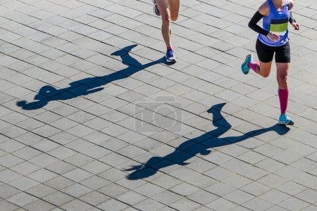 Téléchargez les photos : Vue aérienne deux athlètes féminines course de marathon, ombres de coureuses sur dalles de pavage - en image libre de droit