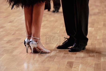 Couple dancers, legs woman in silver shoes and man in black dance shoes