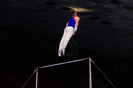 Foto de Gimnasta ejercicio barra horizontal en el campeonato de gimnasia, hombre volador concepto - Imagen libre de derechos
