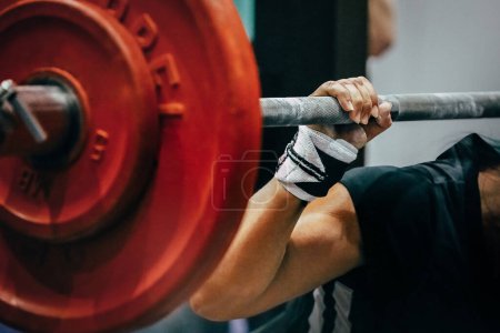 Photo for Close-up red plates barbell and arm female powerlifter during squat - Royalty Free Image