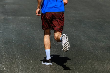 Foto de Suela de zapato running corredor masculino fondo asfalto oscuro, carrera maratón verano - Imagen libre de derechos